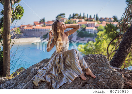Woman tourist on background of beautiful view of the island of St. Stephen, Sveti Stefan on the Budva Riviera, Budva, Montenegro. Travel to Montenegro concept Woman tourist on background of beautiful view of the island of St. Stephen, Sveti Stefan on the Budva Riviera, Budva, Montenegro. Travel to Montenegro concept 90716919