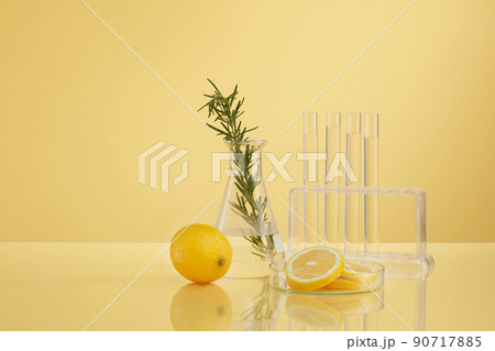 Front view of transparent podium with lemon laboratory equipment and green leaf in beige background science content 90717885