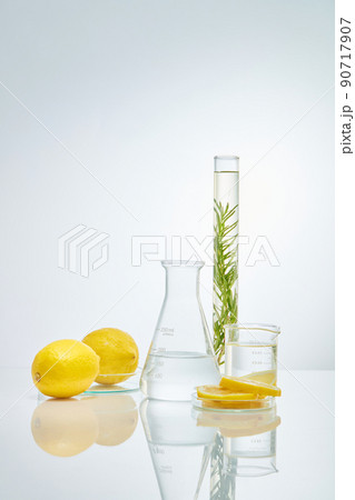 Front view of transparent podium with lemon laboratory equipment and green leaf in white background science content 90717907