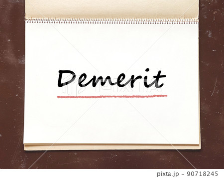 机の上で開いた古いスケッチブックのDemeritの文字入りページ_俯瞰 90718245
