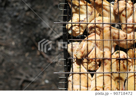 Chicken legs and wings are fried on coals in a brazier in a barbecue grill, marinated chicken is fried on a picnic Chicken legs and wings are fried on coals in a brazier in a barbecue grill, marinated chicken is fried on a picnic 90718472