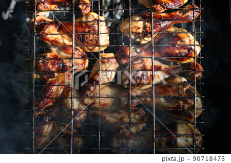 Chicken legs and wings are fried on coals in a brazier in a barbecue grill, marinated chicken is fried on a picnic 90718473
