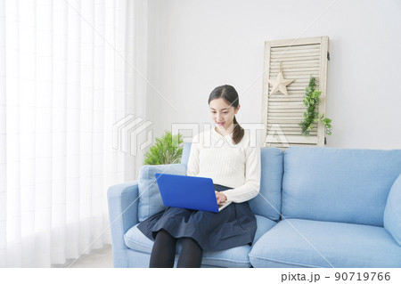 リビングのソファーに座ってノートパソコンを使う女性 90719766