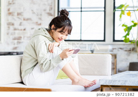リビングでスマホを見る若い女性 90721382
