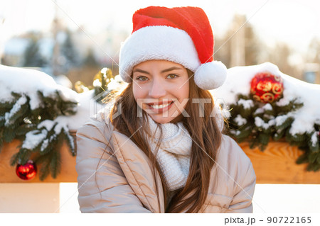 Winter portrait young adult beautiful woman in Santa hat. Christmas mood. Snowing. Winter beauty fashion concept Winter portrait young adult beautiful woman in Santa hat. Christmas mood. Snowing. Winter beauty fashion concept 90722165
