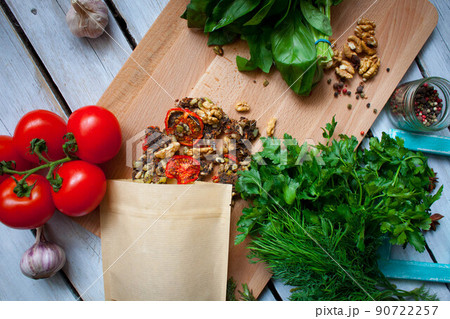 A layout for your product in a package of brown eco-friendly craft paper on a cutting board with tomatoes and green herbs. Copy space for your design. The concept of an ecological lifestyle. 90722257