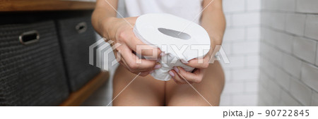 Woman sitting on toilet and hold toilet paper in hands 90722845