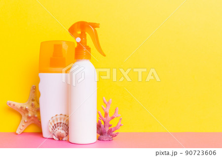 Beach accessories. Moisturiser sunscreen suntan lotion bottle for UVB skincare protection in summer with seashells on colored background. Mock up with copy space 90723606