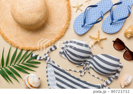 Woman swimwear and beach accessories flat lay top view on colored background Summer travel concept. bikini swimsuit, straw hat and seasheels. Copy space Top view Woman swimwear and beach accessories flat lay top view on colored background Summer travel concept. bikini swimsuit, straw hat and seasheels. Copy space Top view 90723732