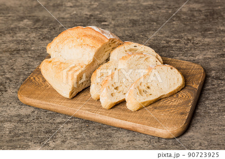 Assortment of freshly sliced baked bread with napkin on rustic table top view. Healthy unleavened bread. French bread slice Assortment of freshly sliced baked bread with napkin on rustic table top view. Healthy unleavened bread. French bread slice 90723925