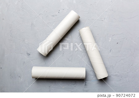 Empty toilet paper roll on colored background. Recyclable paper tube with metal plug end made of kraft paper or cardboard in the form of a recycling sign 90724072