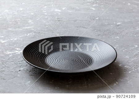 Perspective view of empty black plate on cement background. Empty space for your design 90724109