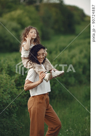 Family in a summer park. Mother in a white t-shirt. Cute little girl Family in a summer park. Mother in a white t-shirt. Cute little girl 90724887