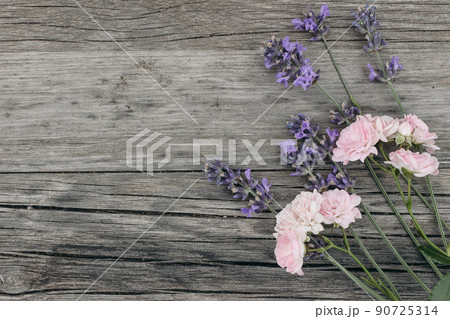Bouquet of lavender flowers and little pink roses on old wooden table background. Decorative floral frame, web banner with Lavandula officinalis. French summer design, aromatherapy concept. 90725314