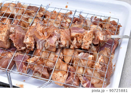 Raw pork meat in a barbecue net with spices 90725881