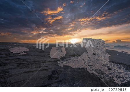 Close-up of iceberg chunk on black sand of Diamond beach against sky at sunset Close-up of iceberg chunk on black sand of Diamond beach against sky at sunset 90729613