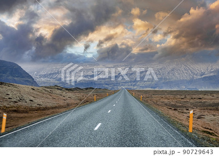 Diminishing road leading towards mountain range against cloudy sky at sunset Diminishing road leading towards mountain range against cloudy sky at sunset 90729643