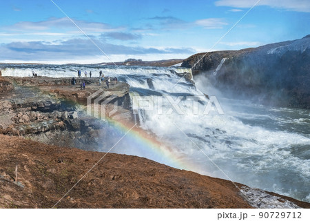 Tourists enjoying view of Gullfoss waterfall in Golden Circle against blue sky Tourists enjoying view of Gullfoss waterfall in Golden Circle against blue sky 90729712