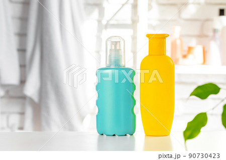 Cosmetic bottles against white bathroom wall background Cosmetic bottles against white bathroom wall background 90730423