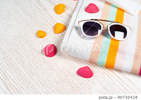 Colorful striped towel with sunglasses and seashells on wooden board 90730428