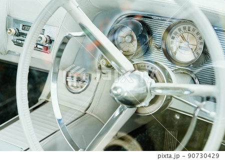 Retro car bright interior, dashboard and steering wheel with controls in classic american car Retro car bright interior, dashboard and steering wheel with controls in classic american car 90730429