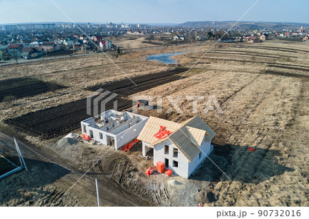 Aerial view of unfinished frame of private house with aerated lightweight concrete walls and wooden roof frame under construction. 90732016