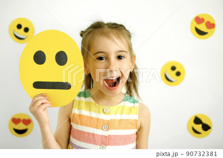 Naughty laughing girl with a sad disappointed smile face emoticon in her hand. World smile face 90732381