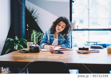 Clever Caucasian hipster girl making notes of organisation plan while drawing sketches 90732399