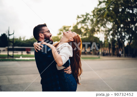 Vivacious female rejoicing and laughing while having fun with cheerful boyfriend holding her in arms 90732452