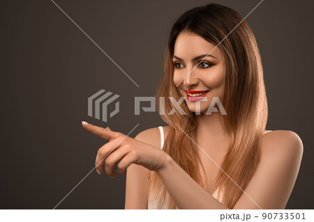 Beautiful Caucasian female model pointing your product. Copyspace 90733501