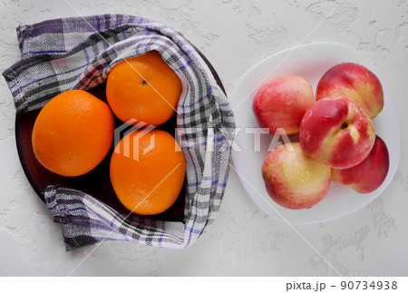 Nectarines and oranges in a plate of fresh fruit. 90734938