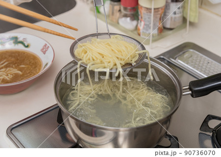 【ミドル主婦がラーメンの麺を菜箸と笊を使って茹でる】 90736070