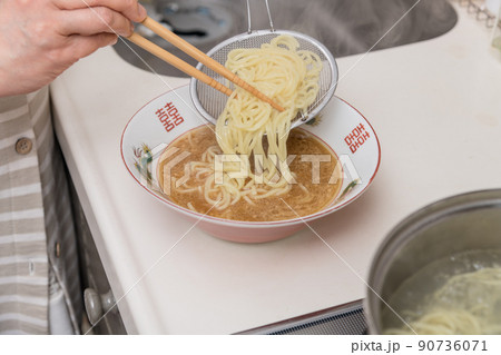 【ミドル主婦が茹で上がったラーメンの麺を器に盛る】 90736071