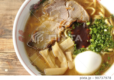 大きなチャーシューとメンマやゆで卵や万能ねぎと辛味噌が乗っている豚骨醤油ラーメンを俯瞰で撮影 大きなチャーシューとメンマやゆで卵や万能ねぎと辛味噌が乗っている豚骨醤油ラーメンを俯瞰で撮影 90737978