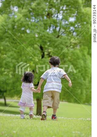 公園を歩く兄と妹の後ろ姿 90739144