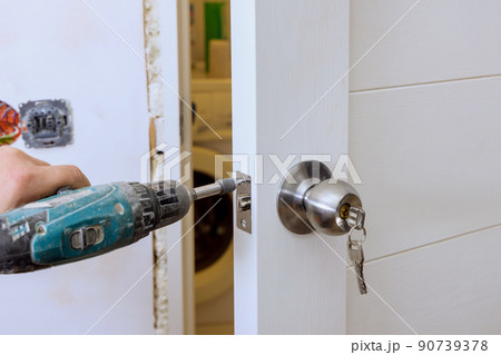 Builder in installing a door lock the door of a new house 90739378