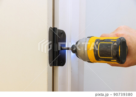 Installing the door hinge on the door frame using a screwdriver a home reconstruction 90739380