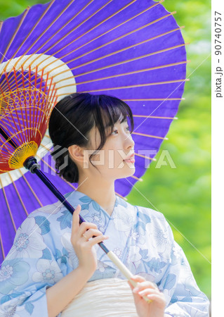 和傘で涼しげに街歩きをする浴衣を着た女性 90740757