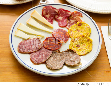Slicing of different varieties of smoked sausages, carbonade, omelet and pieces of hard cheese Slicing of different varieties of smoked sausages, carbonade, omelet and pieces of hard cheese 90741782