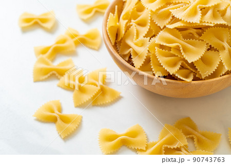 Dry uncooked farfalle pasta in bowl 90743763