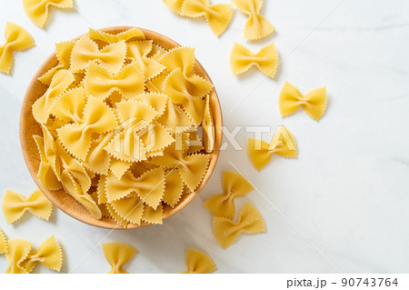 Dry uncooked farfalle pasta in bowl 90743764