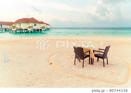 dinner table and chair on beach with sea view background in Maldives 90744156