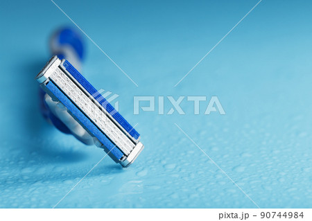 Razor blades on a blue background with drops of icy water 90744984