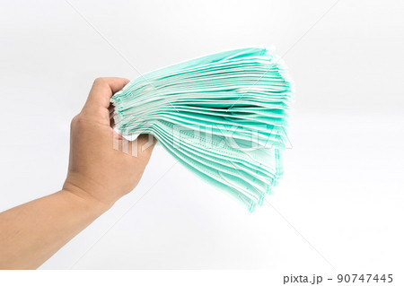 Male's hand holding a lot of health face masks, protect coronavirus (COVID-19) in studio light white background. Male's hand holding a lot of health face masks, protect coronavirus (COVID-19) in studio light white background. 90747445