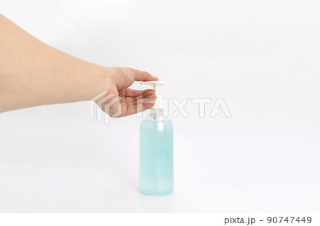 Asian mand hand holds a gel alcohol pump bottle and ready to pushes on it. It's an isolated object on the white clear screen in studio light. 90747449