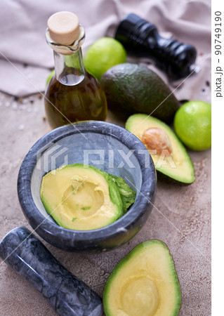 fresh avocado cut in half and marble mortar on grey concrete table 90749190
