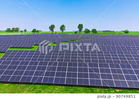 Solar panels battery in green field against blue sky, aerial view. Photovoltaic modules for renewable energy. Concept of clean, sustainable, alternative energy Solar panels battery in green field against blue sky, aerial view. Photovoltaic modules for renewable energy. Concept of clean, sustainable, alternative energy 90749851