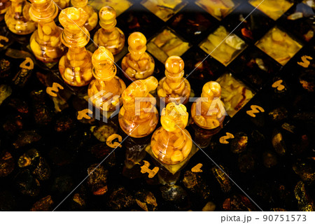 Natural amber different chess pieces figures standing on brown stone board. Close up game concept competition, Classic Gambit Tournament of confrontation. 90751573