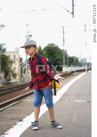 6 year old boy with backpack. posing on the train platform on summer day. rails on background 6 year old boy with backpack. posing on the train platform on summer day. rails on background 90752129