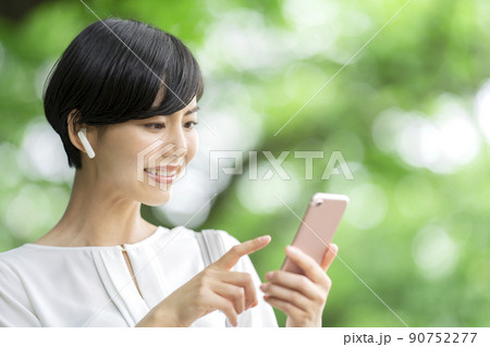 スマホで音楽を聴く若い女性　スマホを操作する若い女性　屋外 90752277